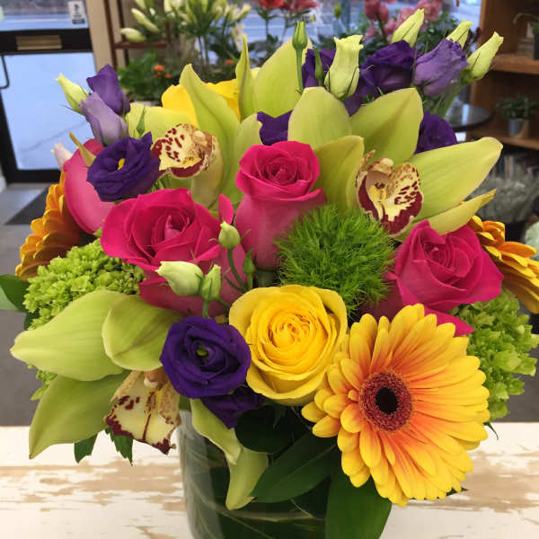 Colorful bouquet of roses, lilies, and gerbera daisies in a glass vase