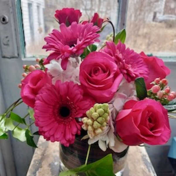 Pink roses and gerbera daisies arranged in a glass vase