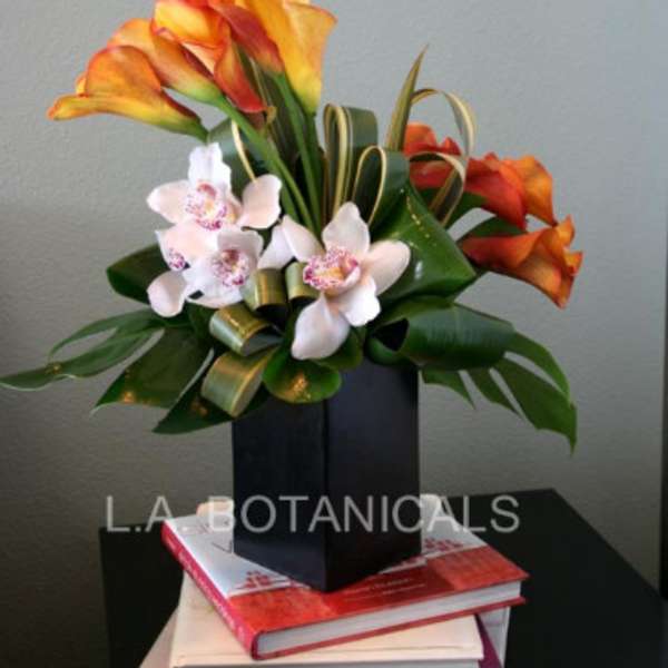 Orange calla lilies and white orchids in a black box arrangement