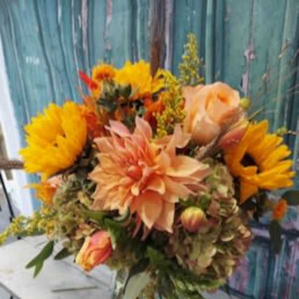 Bouquet of sunflowers, peach dahlias, and roses in a glass vase