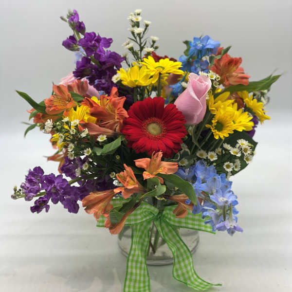 Colorful mixed bouquet in a clear glass vase with a green gingham ribbon