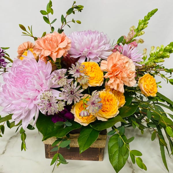 Mixed bouquet of pink, peach, and yellow flowers in a wooden box