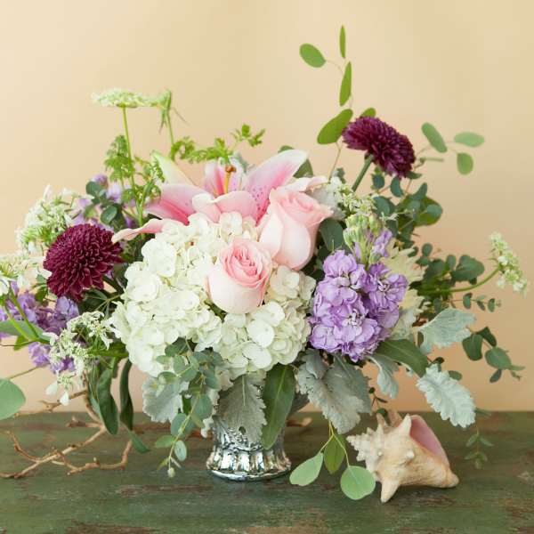 Pink lilies and roses in a silver vase with white and purple flowers