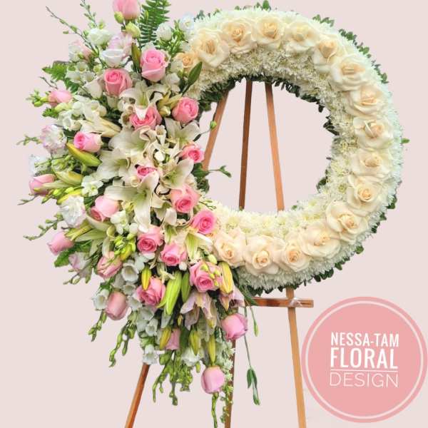 Floral wreath on an easel with pink and cream roses and lilies