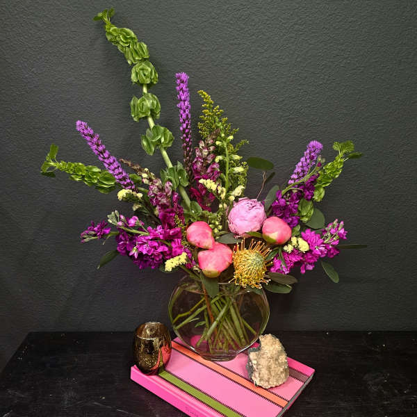 Mixed bouquet of pink and purple flowers in a round glass vase
