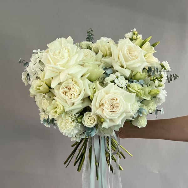White rose bridal bouquet with pale filler flowers and ribbon tails