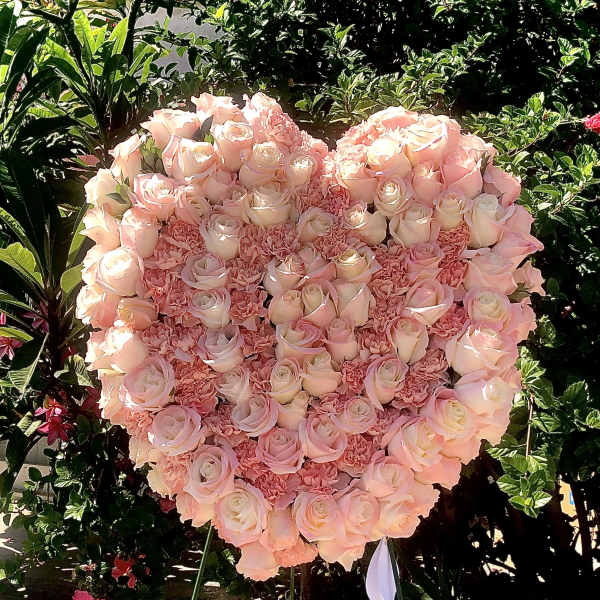 Heart-shaped pink rose and carnation standing spray on a metal easel