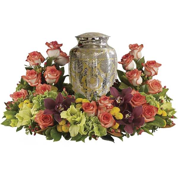 Floral urn arrangement with coral roses and orchids around a silver urn