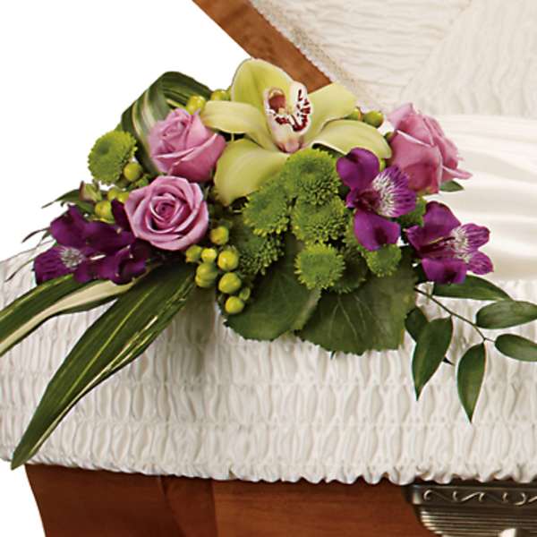 Floral casket spray with pink roses, green orchids, and purple blooms