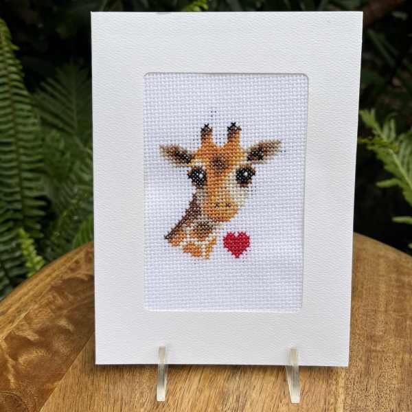 Cross-stitch greeting card with a giraffe and red heart