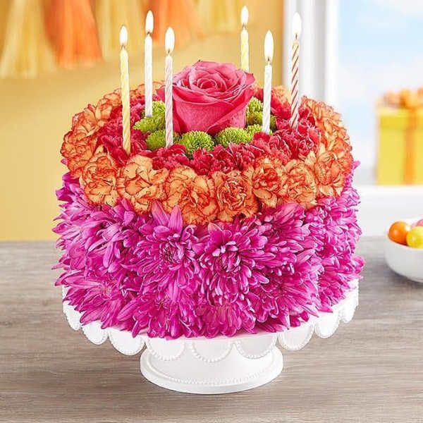 Round floral cake with candles and a pink rose centerpiece