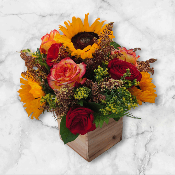 Arrangement of sunflowers and red and orange roses in a wooden cube vase