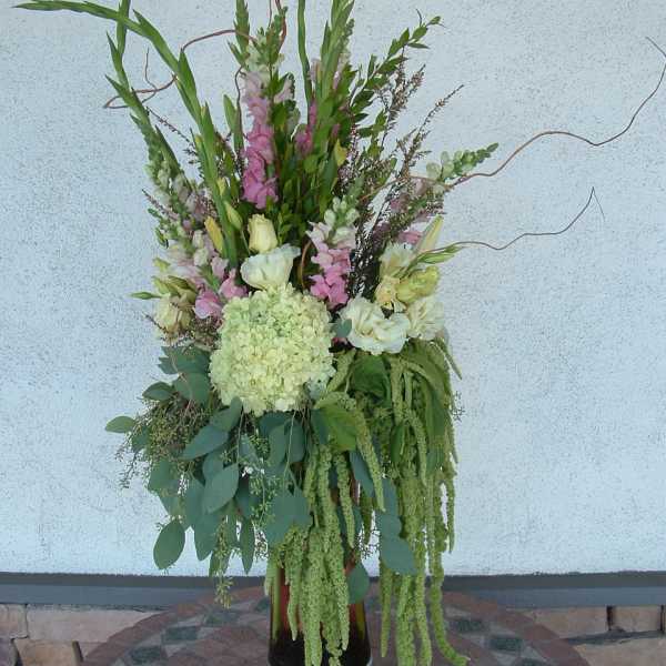 Tall floral arrangement with pink and white blooms in a black vase