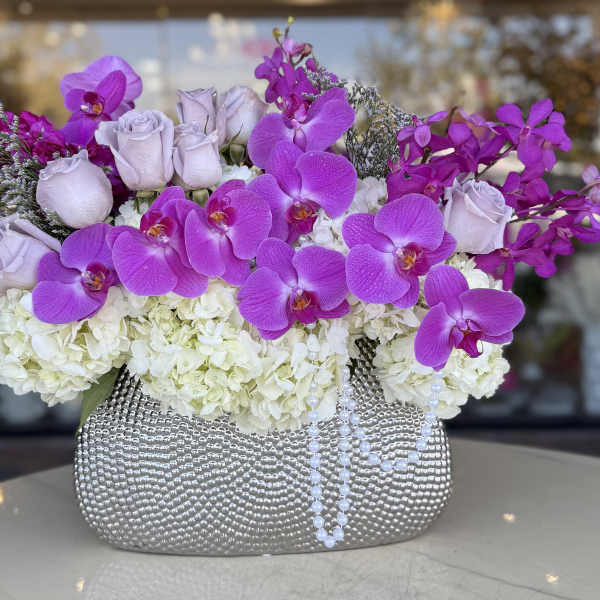 Purple orchids and pale roses in a silver textured vase