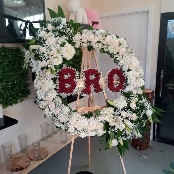 Large floral wreath on an easel with red letters in the center