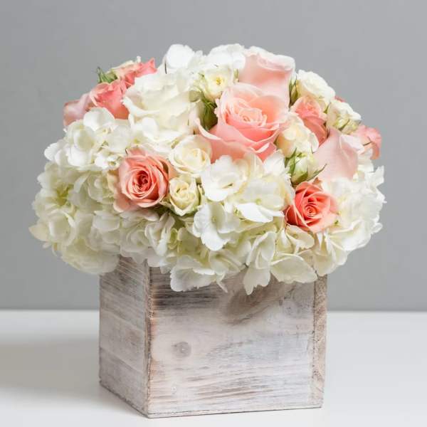 Pink and white roses arranged in a rustic wooden box