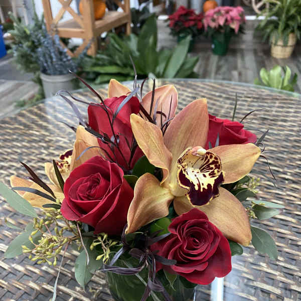 Red roses and orchids arranged in a glass vase