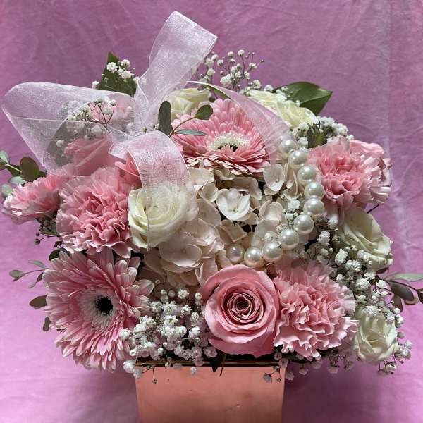 Pink and white flower arrangement in a square box with a sheer ribbon