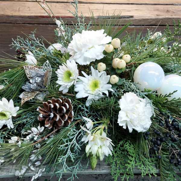 Low winter arrangement with white flowers, pinecones, and ornaments