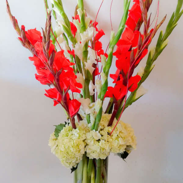 Tall red and white floral arrangement in a clear glass vase