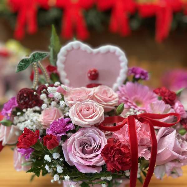 Pink rose bouquet with red carnations and a heart topper in a pink box