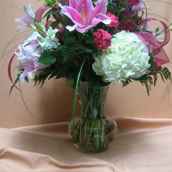 Pink lilies and red roses arranged in a clear glass vase