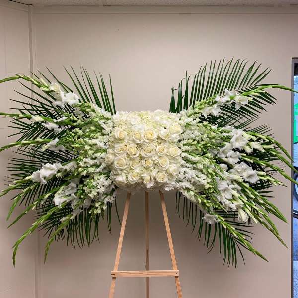 Large white floral spray with roses and lilies on an easel