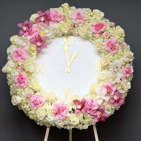 Round floral clock covered in pink and white roses and orchids
