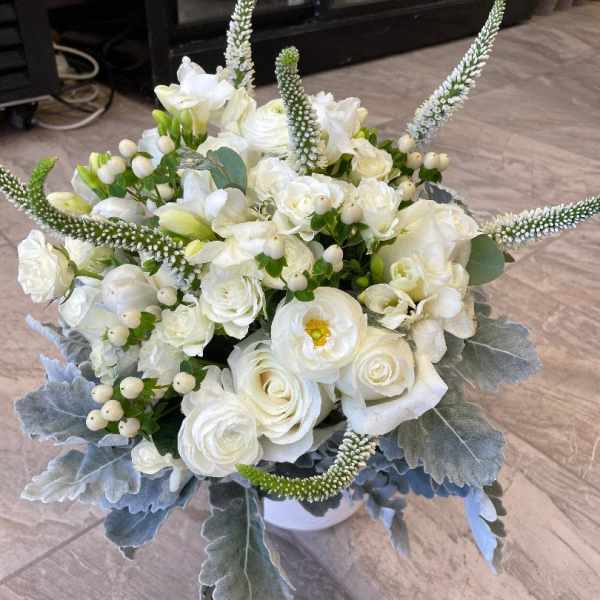White floral bouquet with tall spiky accents in a white container