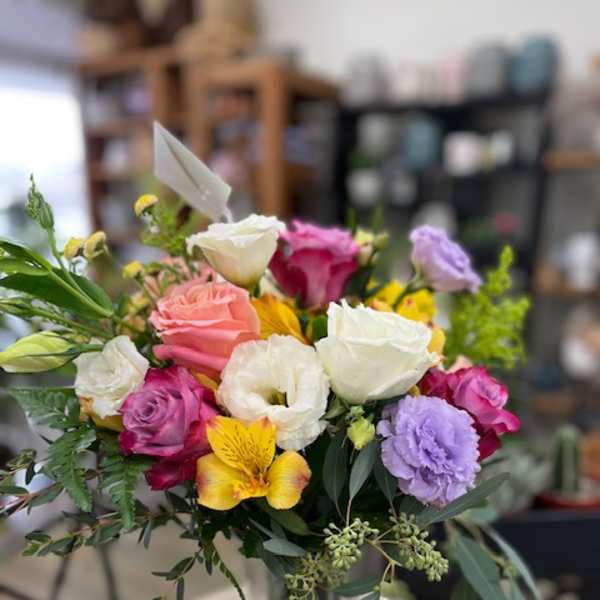 Mixed bouquet of roses, lisianthus, and alstroemeria in a glass vase
