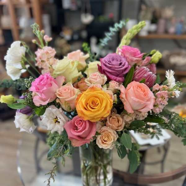 Mixed bouquet of roses and other blooms in a glass vase