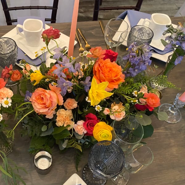 Colorful floral centerpiece with roses, daffodils, and purple blooms on a table