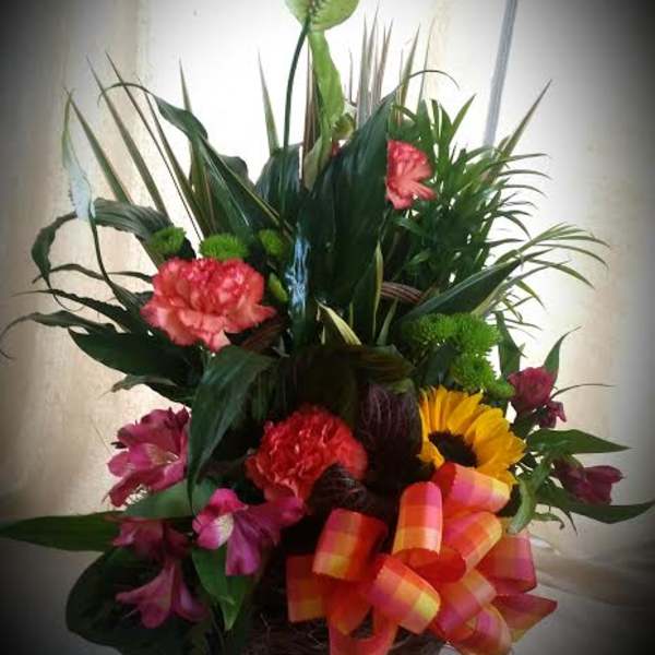 Mixed floral basket with carnations, sunflower, and tropical foliage