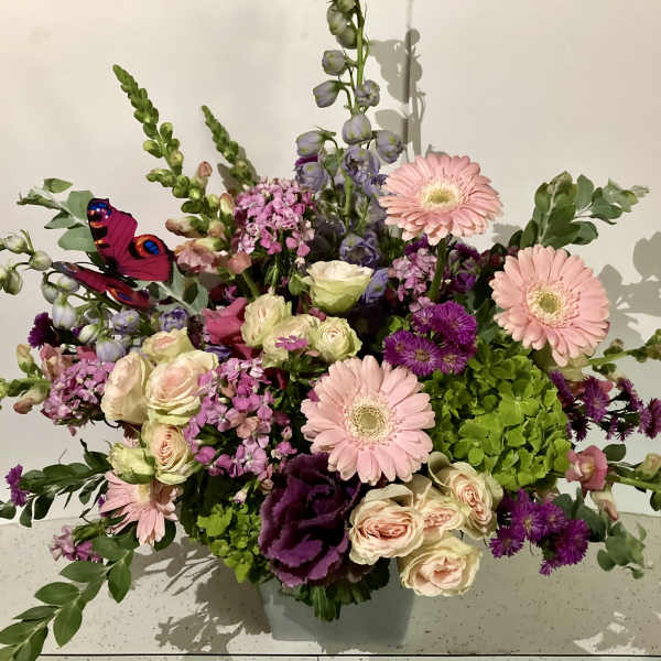 Mixed bouquet with pink gerbera daisies, roses, and purple blooms in a vase
