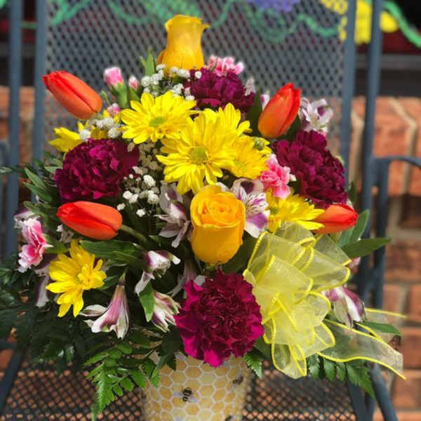 Bright mixed bouquet in a honeycomb-patterned vase with yellow ribbon