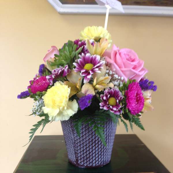 Mixed bouquet in a purple woven vase with pink and yellow blooms