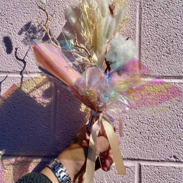 Dried bouquet with white fluffy grasses and iridescent wrap
