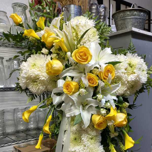 Large yellow and white floral standing spray with roses, lilies, and chrysanthemums