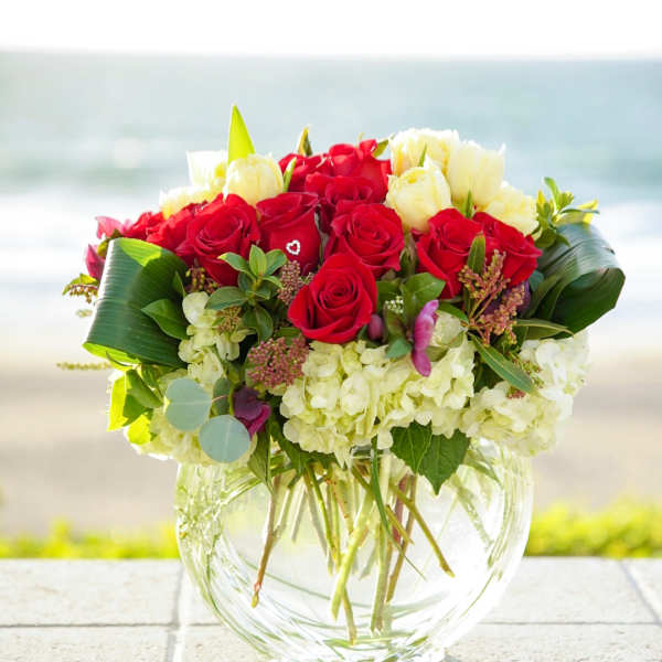 Red and white rose bouquet in a clear glass vase