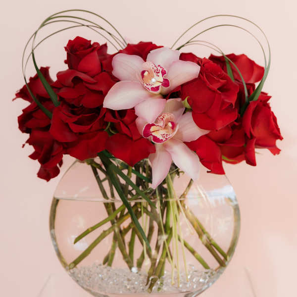 Red roses and pale pink orchids in a clear glass vase