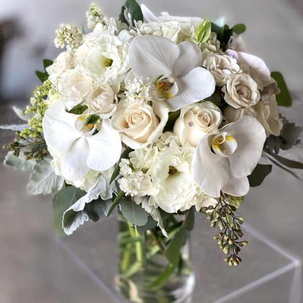 White bouquet of orchids and roses in a clear glass vase
