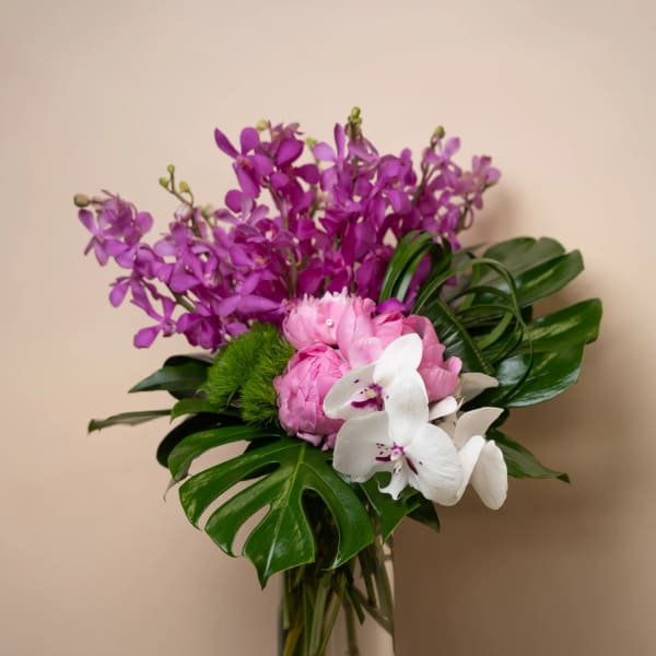 Purple and white orchid bouquet in a tall glass vase