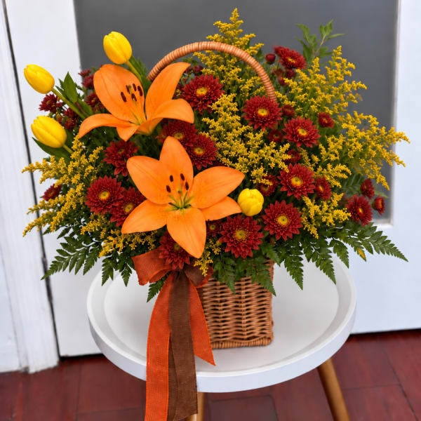 Basket arrangement with orange lilies, yellow tulips, and red mums