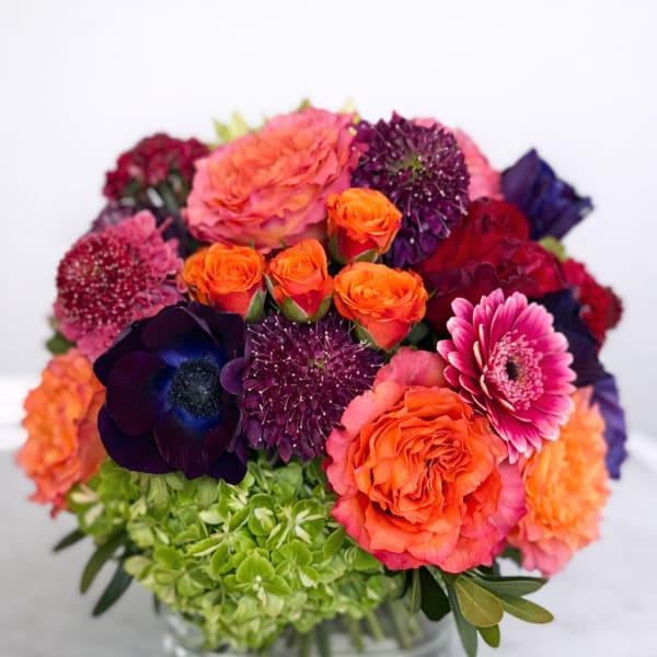 Colorful bouquet of roses, gerbera daisies, and hydrangeas in a glass vase