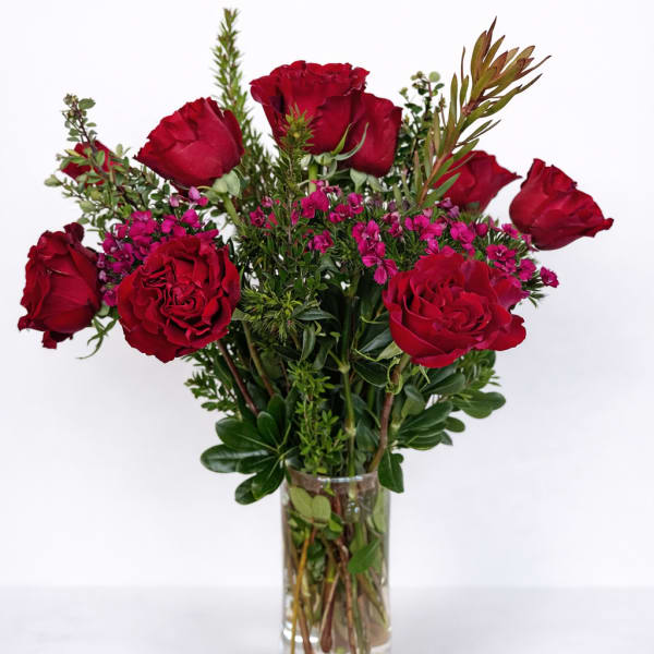 Red roses and pink filler flowers in a clear glass vase