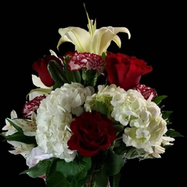Bouquet of red roses, white hydrangeas, and white lilies in a clear vase