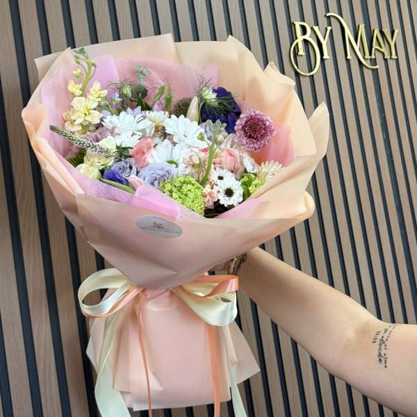 Pastel mixed flower bouquet wrapped in pink paper with ribbon