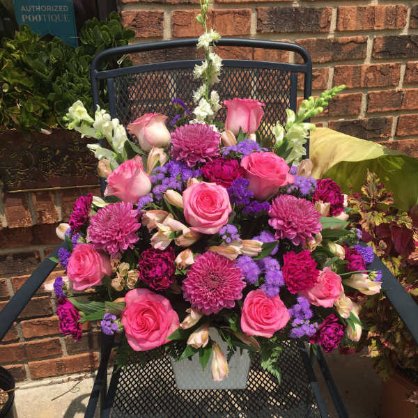 Pink and purple mixed flower arrangement in a white container
