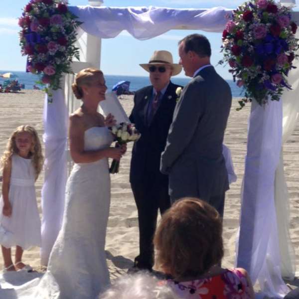 Beach wedding arch decorated with pink and purple flowers