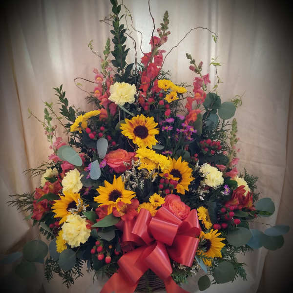 Large mixed flower basket with sunflowers, roses, and a red bow